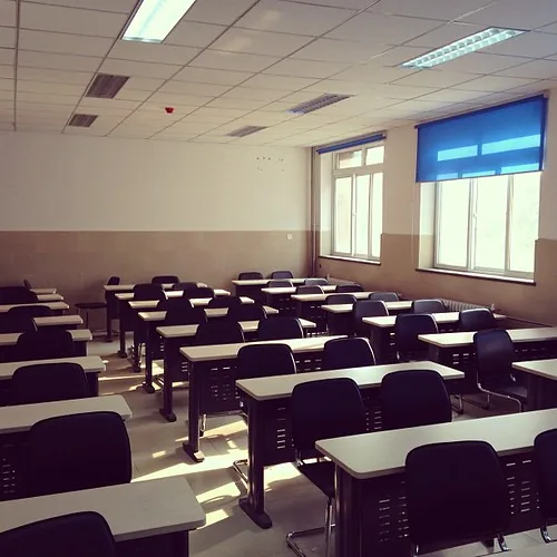 Aula con persianas azules y luz natural, filas de pupitres (fotografía ilustrativa)