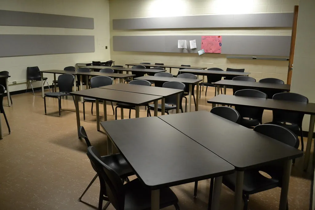 Aula moderna con mesas grises y sillas negras, lista para clase (fotografía ilustrativa)