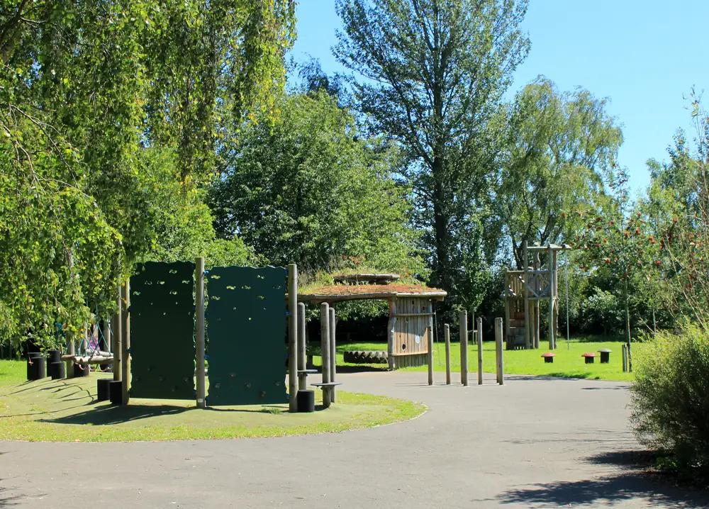 Patio y área de juegos al aire libre entre árboles (fotografía ilustrativa)